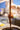 A gloved hand holds an ice cream cone under a stream of melted chocolate, coating the cone with a glossy layer. The background is softly blurred. - AI generated text