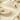 Smooth, creamy beige gelato or ice cream with swirled textures, decorated with clusters of whole hazelnuts on top. - AI generated text