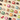 Assorted wrapped and unwrapped chocolates are arranged in a neat grid on a beige surface, with a few pieces of fruit and caramel scattered among the colorful candy wrappers. - AI generated text