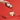 A hand sprinkles cocoa powder from a decorative tin onto a round dessert resting on a gold stand, with a vibrant red background. - AI generated text