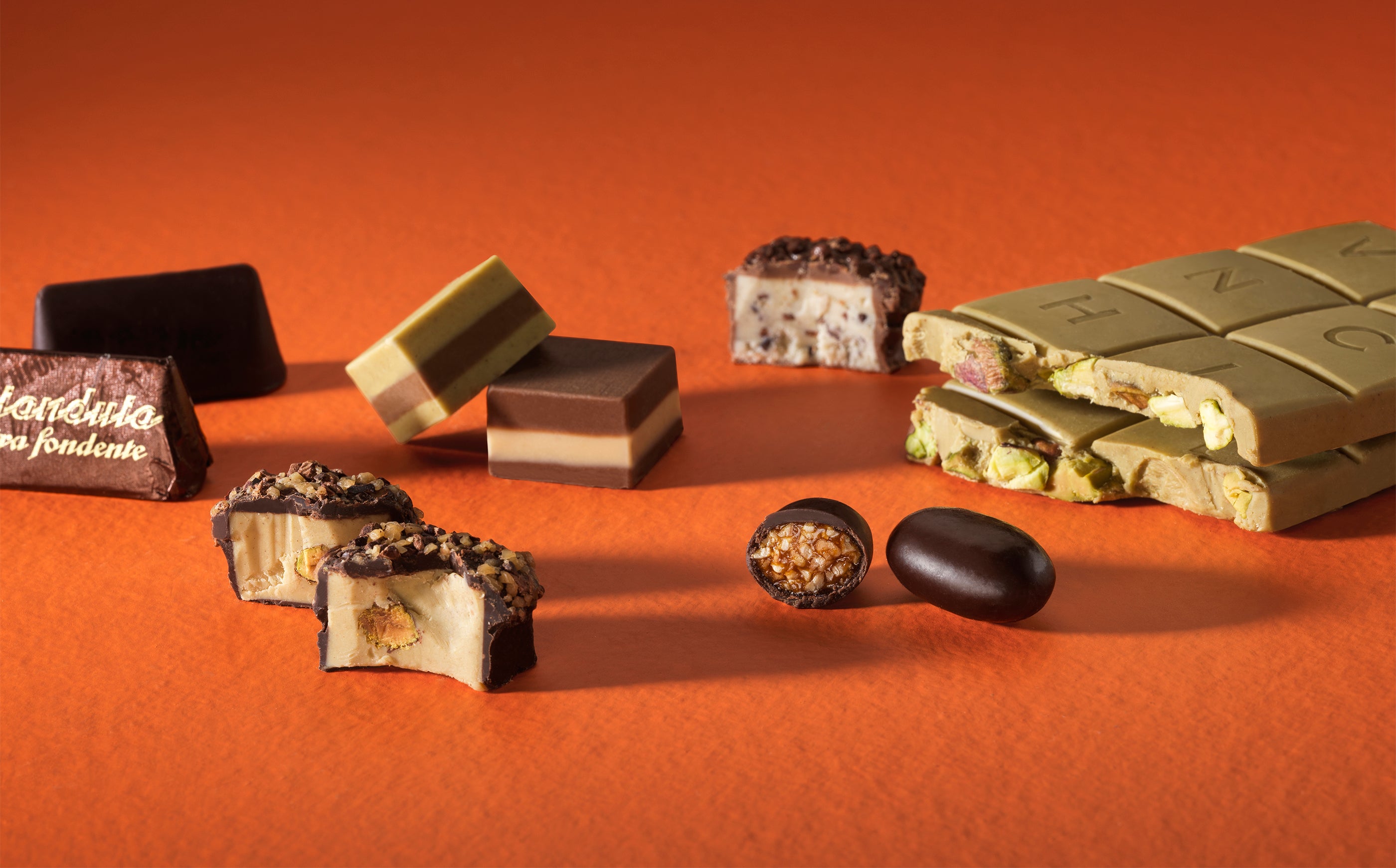 An assortment of chocolates, chocolate bars, and pralines with various layers, fillings, and coatings are arranged on an orange surface against an orange background. - AI generated text