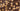 Close-up of a chocolate bar with whole and halved hazelnuts embedded throughout the surface, showing the glossy, smooth texture of the chocolate and the rough, light brown nuts. - AI generated text