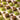 An arrangement of green foil-wrapped pistachio chocolates and unwrapped chocolates coated in chopped nuts, with scattered pistachio nuts on a light-colored surface. - AI generated text