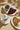Three plates on a beige surface: a steaming cup of hot chocolate with whipped cream, a chocolate tart with berry topping and whipped cream, and crepes drizzled with chocolate sauce and caramel, all garnished with chocolate sprinkles. - AI generated text