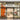 Storefront of Venchi with large glass doors, a well-lit interior displaying chocolates and treats, orange seating on the left, two cone-shaped displays outside, and a sign above the entrance with the Venchi logo. - AI generated text