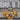 A stylish Venchi chocolate and gelato shop with ornate gray and white exterior, large windows displaying colorful treats inside, and two tall chairs with sculpted white seats outside the entrance. - AI generated text