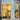 A modern Venchi store with large glass windows and floral-patterned walls, glowing warmly from interior golden lighting that highlights displays of chocolate products. Trees and a sidewalk are visible in front of the building. - AI generated text